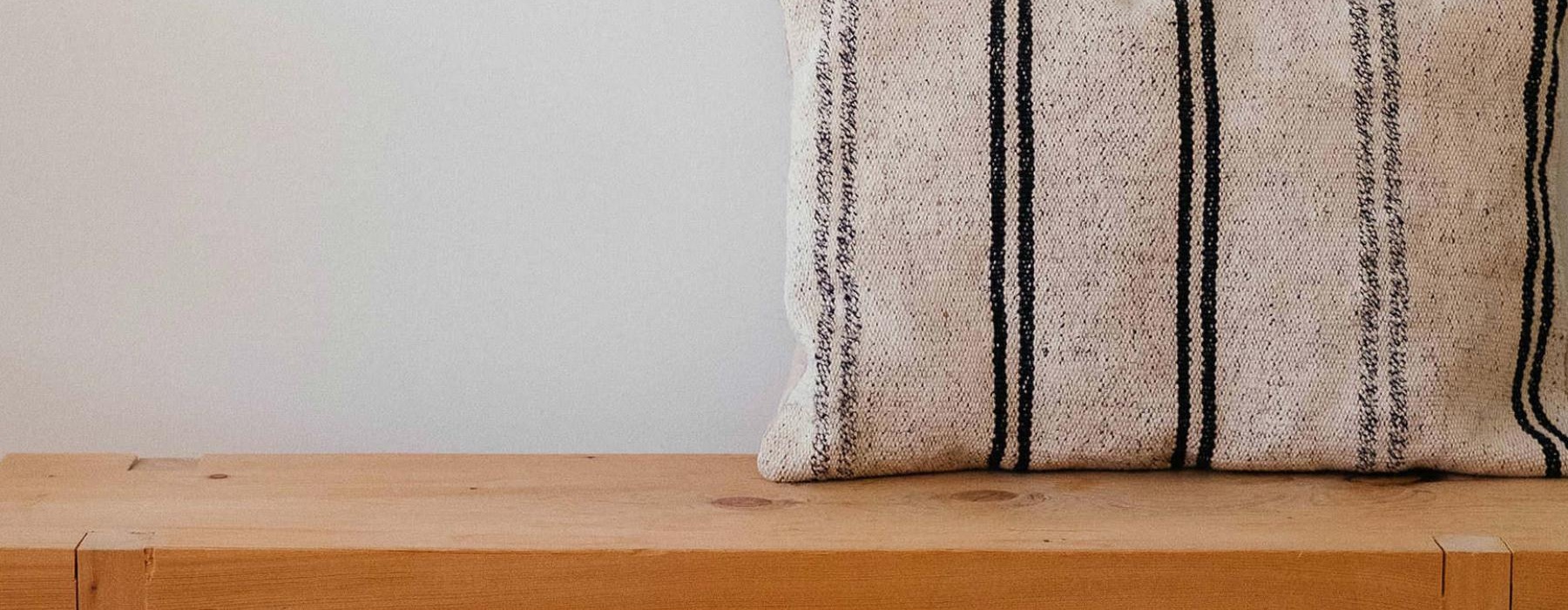 a wooden bench with a striped pillow on it